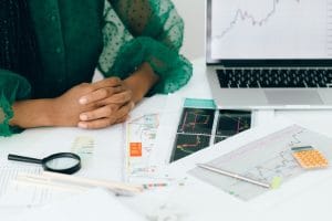Hands resting on a table with charts and a laptop displaying data analysis.